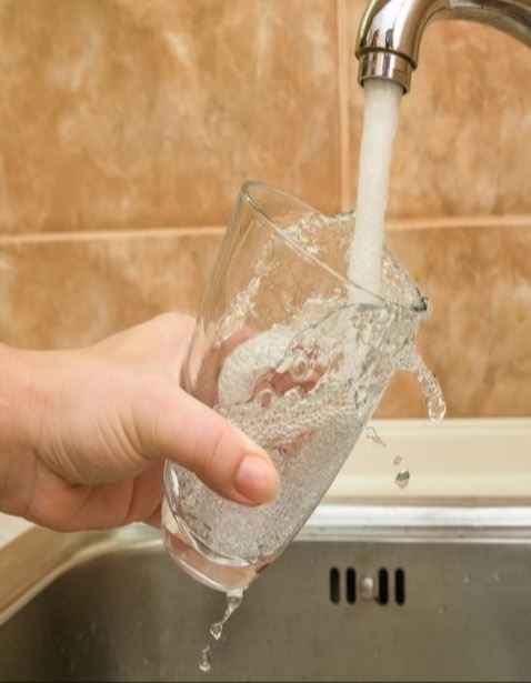 a glass filling with water from the faucet